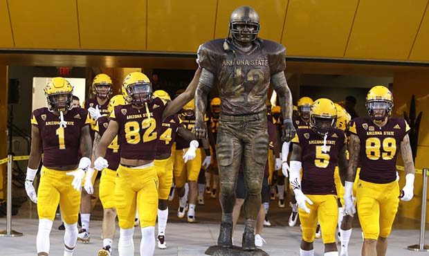 Arizona State's Josh Pokraka (82) and teammates touch the Pat Tillman statue before an NCAA college...