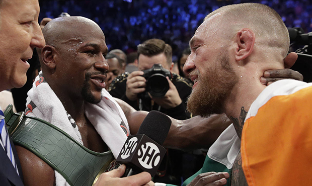 Floyd Mayweather Jr., left, speaks with Conor McGregor after a super welterweight boxing match Satu...