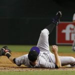 Colorado Rockies' Mark Reynolds loses the baseball on a short hop throw from Nolan Arenado was unable to get Arizona Diamondbacks' J.D. Martinez at first base during the eighth inning of a baseball game Monday, Sept. 11, 2017, in Phoenix. The Rockies defeated the Diamondbacks 5-4. (AP Photo/Ross D. Franklin)