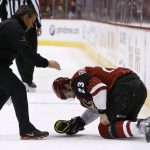 Arizona Coyotes' Oliver Ekman-Larsson (23) grabs his left knee as a Coyotes trainer arrives to help, during the third period of a preseason NHL hockey game against the San Jose Sharks on Saturday, Sept. 23, 2017, in Glendale, Ariz. The Sharks defeated the Coyotes 5-4 in a shootout. (AP Photo/Ross D. Franklin)
