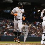 San Francisco Giants' Denard Span, left, scores a run on a double by Pablo Sandoval as Arizona Diamondbacks' Chris Herrmann, right, pauses at home plate during the first inning of a baseball game Wednesday, Sept. 27, 2017, in Phoenix. (AP Photo/Ross D. Franklin)