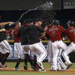 Arizona Diamondbacks players, including Adam Rosales (9), Daniel Descalso (3) and David Peralta (6), celebrate a walk off single by J.D. Martinez as they clinch a National League Wild Card playoff spot in the ninth inning of a baseball game against the Miami Marlins, Sunday, Sept. 24, 2017, in Phoenix. The Diamondbacks defeated the Marlins 3-2. (AP Photo/Ross D. Franklin)