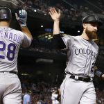 Colorado Rockies' Jonathan Lucroy, right, gets a high-five from Nolan Arenado (28) after Lucroy scored a run against the Arizona Diamondbacks during the third inning of a baseball game, Monday, Sept. 11, 2017, in Phoenix. (AP Photo/Ross D. Franklin)