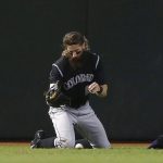 Colorado Rockies' Charlie Blackmon reaches for a baseball hit by Arizona Diamondbacks' Chris Iannetta as Blackmon would have the ball pop out of his glove diving for the Iannetta line drive and Iannetta would get a double on the play during the first inning of a baseball game Thursday, Sept. 14, 2017, in Phoenix. (AP Photo/Ross D. Franklin)