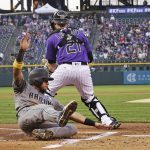 Arizona Diamondbacks' David Peralta, bottom, slides safely into home plate against Colorado Rockies catcher Jonathan Lucroy (21) during the first inning of a baseball game Friday, Sept. 1, 2017, in Denver. (AP Photo/Jack Dempsey)