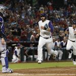 Colorado Rockies' Tony Wolters, left, waits for a possible throw as Arizona Diamondbacks' J.D. Martinez, middle, and Brandon Drury, right, run home to score runs on a double by A.J. Pollock during the first inning of a baseball game Thursday, Sept. 14, 2017, in Phoenix. (AP Photo/Ross D. Franklin)