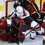 Arizona Coyotes' Mike Sislo, right, crashes into Calgary Flames goalie Mike Smith during the second period of a preseason NHL hockey game, Friday, Sept. 22, 2017 in Calgary, Alberta. (John McIntosh/The Canadian Press via AP)