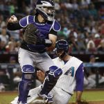 Colorado Rockies' Tony Wolters, left, looks to throw the ball after forcing out Arizona Diamondbacks' Chris Iannetta, right, at home plate during the first inning of a baseball game Thursday, Sept. 14, 2017, in Phoenix. (AP Photo/Ross D. Franklin)