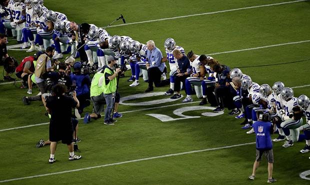 The Dallas Cowboys, led by owner Jerry Jones, center, take a knee prior to the national anthem prio...