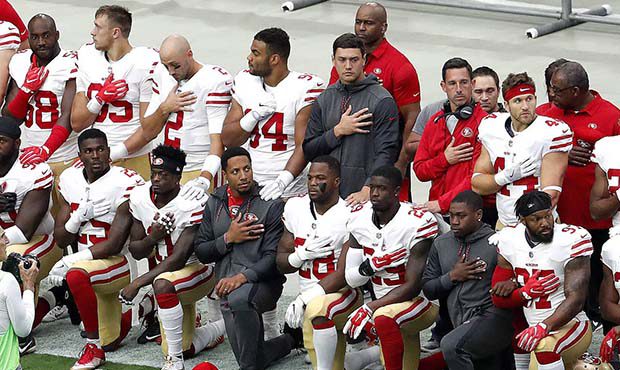Members of the San Francisco 49ers kneel during the national anthem as others stand prior to an NFL...