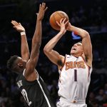 Brooklyn Nets guard Caris LeVert (22) defends Phoenix Suns guard Devin Booker (1) who loses control of the ball while shooting for two points in the second half of an NBA basketball game, Tuesday, Oct. 31, 2017, in New York. The Suns defeated the Nets 122-114. (AP Photo/Kathy Willens)