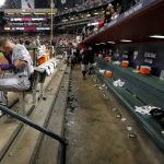 Colorado Rockies shortstop Trevor Story sits in the dugout as the Arizona Diamondbacks celebrate after the National League wild-card playoff baseball game Wednesday, Oct. 4, 2017, in 
Phoenix. The Diamondbacks won 11-8 to advance to an NLDS against the Los Angeles Dodgers. (AP Photo/Matt York)