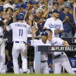 Los Angeles Dodgers' Logan Forsythe celebrates in the dugout after scoring on a wild pitch during the fourth inning of Game 2 of baseball's National League Division Series against the Arizona Diamondbacks in Los Angeles, Saturday, Oct. 7, 2017. (AP Photo/Mark J. Terrill)