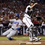 Los Angeles Dodgers' Chris Taylor (3) scores on an RBI ground out by Cody Bellinger as Arizona Diamondbacks catcher Jeff Mathis waits for the throw during the first inning of game 3 of baseball's National League Division Series, Monday, Oct. 9, 2017, in Phoenix. (AP Photo/Ross D. Franklin)
