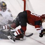 Arizona Coyotes' Christian Dvorak, right, gets sent into the air after his shot was blocked by Chicago Blackhawks' Corey Crawford, left, during the first period of an NHL hockey game Saturday, Oct. 21, 2017, in Glendale, Ariz. (AP Photo/Ross D. Franklin)