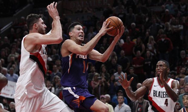 Phoenix Suns guard Devin Booker, center, shoots as Portland Trail Blazers center Jusuf Nurkic, left...