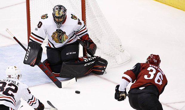 Arizona Coyotes' Christian Fischer (36) sends the puck at Chicago Blackhawks' Corey Crawford (50) b...
