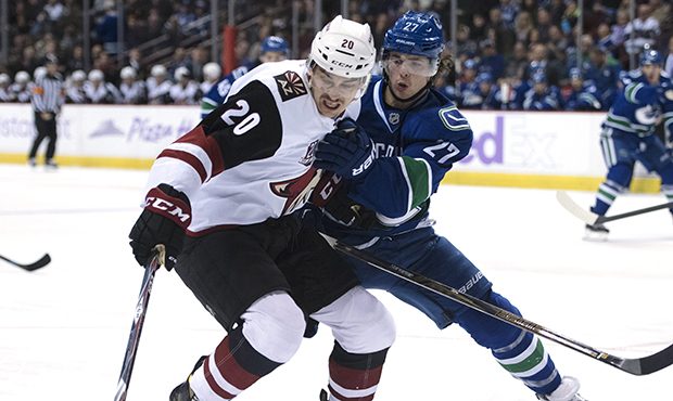 Vancouver Canucks defenseman Ben Hutton (27) fights for control of the puck with Arizona Coyotes ce...