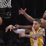 Los Angeles Lakers forward Kyle Kuzma, center, is hit in the face by Phoenix Suns guard Devin Booker, below, as he passes the ball while under pressure from Suns forward TJ Warren during the second half of an NBA basketball game, Friday, Nov. 17, 2017, in Los Angeles. The Suns won 122-113. (AP Photo/Mark J. Terrill)