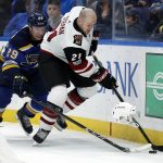 Arizona Coyotes' Derek Stepan (21) loses his helmet while reaching for a loose puck with St. Louis Blues' Vince Dunn (29) during the third period of an NHL hockey game Thursday, Nov. 9, 2017, in St. Louis. The Blues won 3-2 in a shootout. (AP Photo/Jeff Roberson)