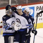 Winnipeg Jets goalie Steve Mason (35) celebrates a win against the Arizona Coyotes with Jets defenseman Tyler Myers (57) and defenseman Dmitry Kulikov (5) after the third period of an NHL hockey game Saturday, Nov. 11, 2017, in Glendale, Ariz. The Jets defeated the Coyotes 4-1. (AP Photo/Ross D. Franklin)
