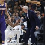 San Antonio Spurs head coach Gregg Popovich helps up Brandon Paul after he draw a charge against Phoenix Suns Devin Booker, left, during the first half of an NBA game on Sunday, Nov. 5, 2017 in San Antonio. (AP Photo/Ronald Cortes)