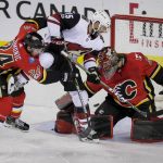 Arizona Coyotes' Brad Richardson watches the puck go past Calgary Flames goalie Mike Smith as Flames' Travis Hamonic defends during the first period of an NHL hockey game Thursday, Nov. 30, 2017, in Calgary, Alberta. (Lyle Aspinall/The Canadian Press via AP)