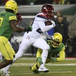Arizona's Nick Wilson, center, rushes between Oregon's Ugochukwu Amadi, left, and Arrion Springs on his way to a touchdown during the second quarter of an NCAA college football game, Saturday, Nov. 18, 2017, in Eugene, Ore. (AP Photo/Chris Pietsch)