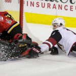 Arizona Coyotes' Christian Dvorak falls beside Calgary Flames goalie Mike Smith during the first period of an NHL hockey game Thursday, Nov. 30, 2017, in Calgary, Alberta. (Lyle Aspinall/The Canadian Press via AP)
