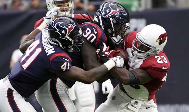 Arizona Cardinals running back Adrian Peterson (23) is stopped by Houston Texans defenders Jadeveon...