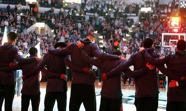 Members of the Phoenix Suns stand arm-in-arm during a moment of silence for the victims of a deadly...