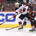 New Jersey Devils' Jimmy Hayes (10) send the puck past Arizona Coyotes' Oliver Ekman-Larsson (23) during the first period of an NHL hockey game, Saturday, Dec. 2, 2017, in Glendale, Ariz. (AP Photo/Ralph Freso)