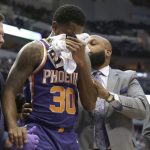 Phoenix Suns guard Troy Daniels (30) is helped off the court after he took a hard hit to the face during the first half of an NBA basketball game against the Dallas Mavericks in Dallas, Monday, Dec. 18, 2017. (AP Photo/LM Otero)