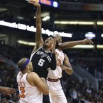 San Antonio Spurs guard Dejounte Murray (5) has his shot blocked by Phoenix Suns' T.J. Warren, right, as he drives to the basket against Suns' Jared Dudley (3) during the first half of an NBA basketball game Saturday, Dec. 9, 2017, in Phoenix. The Spurs defeated the Suns 104-101. (AP Photo/Ralph Freso)