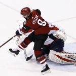 Arizona Coyotes center Clayton Keller (9) pushes the puck into position next to Washington Capitals goalie Philipp Grubauer, right, for the game-tying goal by teammate Christian Fischer during the third period of an NHL hockey game, Friday, Dec. 22, 2017, in Glendale, Ariz. The Coyotes defeated the Capitals 3-2 in overtime. (AP Photo/Ross D. Franklin)