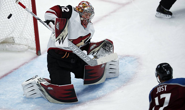 Arizona Coyotes goalie Antti Raanta, left, of Finland, deflects as hot by Colorado Avalanche center...