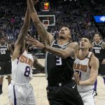 Sacramento Kings guard George Hill, center, goes to the basket between Phoenix Suns' Tyler Ulis, left, and Alex Len, right, during the first quarter of an NBA basketball game Tuesday, Dec. 12, 2017, in Sacramento, Calif. (AP Photo/Rich Pedroncelli)