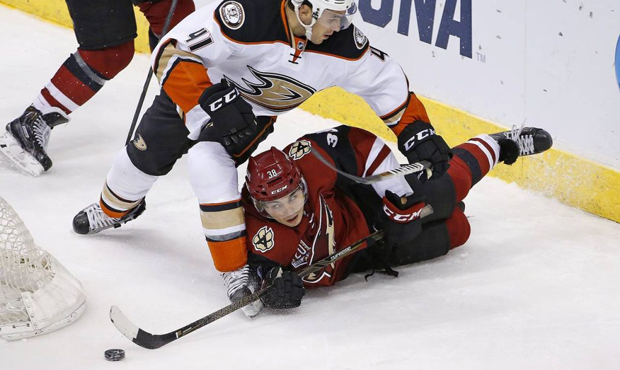 Arizona Coyotes' Nick Merkley (38) tries to get off a shot as he is sent to the ice by Anaheim Duck...