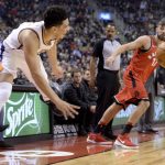 Phoenix Suns guard Devin Booker, left, passes the ball as Toronto Raptors center Jonas Valanciunas (17) watches during the first half of an NBA basketball game Tuesday, Dec. 5, 2017, in Toronto. (Nathan Denette/The Canadian Press via AP