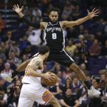 San Antonio Spurs guard Patty Mills (8) leaps to defend Phoenix Suns' Mike James (55) during the second half of an NBA basketball game Saturday, Dec. 9, 2017, in Phoenix. The Spurs defeated the Suns 104-101. (AP Photo/Ralph Freso)