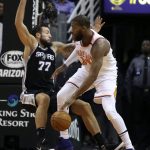 San Antonio Spurs forward Joffrey Lauvergne (77) falls as Phoenix Suns' Greg Monroe drives to the basket during the first half of an NBA basketball game Saturday, Dec. 9, 2017, in Phoenix. (AP Photo/Ralph Freso)