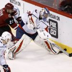 Washington Capitals goalie Philipp Grubauer (31) passes the puck as Arizona Coyotes center Derek Stepan (21) and Capitals center Evgeny Kuznetsov (92) close in during the first period of an NHL hockey game, Friday, Dec. 22, 2017, in Glendale, Ariz. (AP Photo/Ross D. Franklin)