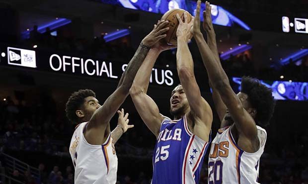 Philadelphia 76ers' Ben Simmons, center, goes up to shoot between Phoenix Suns' Marquese Chriss, le...