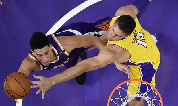 Phoenix Suns guard Devin Booker, left, shoots as Los Angeles Lakers center Brook Lopez defends duri...