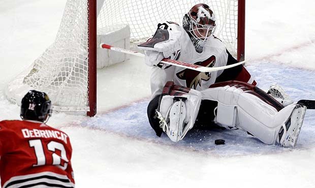 Arizona Coyotes goalie Scott Wedgewood, right, saves a shot by Chicago Blackhawks right wing Alex D...