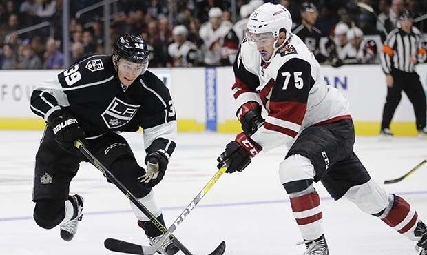 Los Angeles Kings' Adrian Kempe, left, is pressured by Arizona Coyotes' Kyle Capobianco during the ...