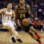 Atlanta Hawks guard Kent Bazemore (24) goes to the basket as Phoenix Suns guard Devin Booker defends in the first half during an NBA basketball game, Tuesday, Jan. 2, 2018, in Phoenix. (AP Photo/Rick Scuteri)