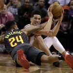 Phoenix Suns guard Devin Booker (1) and Atlanta Hawks guard Kent Bazemore vie for a loose ball in the second half during an NBA basketball game Tuesday, Jan. 2, 2018, in Phoenix. The Suns defeated the Hawks 104-103. (AP Photo/Rick Scuteri)