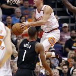 Phoenix Suns guard Devin Booker drives over Houston Rockets forward Trevor Ariza (1) during the first half of an NBA basketball game, Friday, Jan. 12, 2018, in Phoenix. (AP Photo/Matt York)