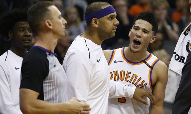 Phoenix Suns guard Devin Booker, right, is held back by teammate Jared Dudley, middle, as Booker ar...